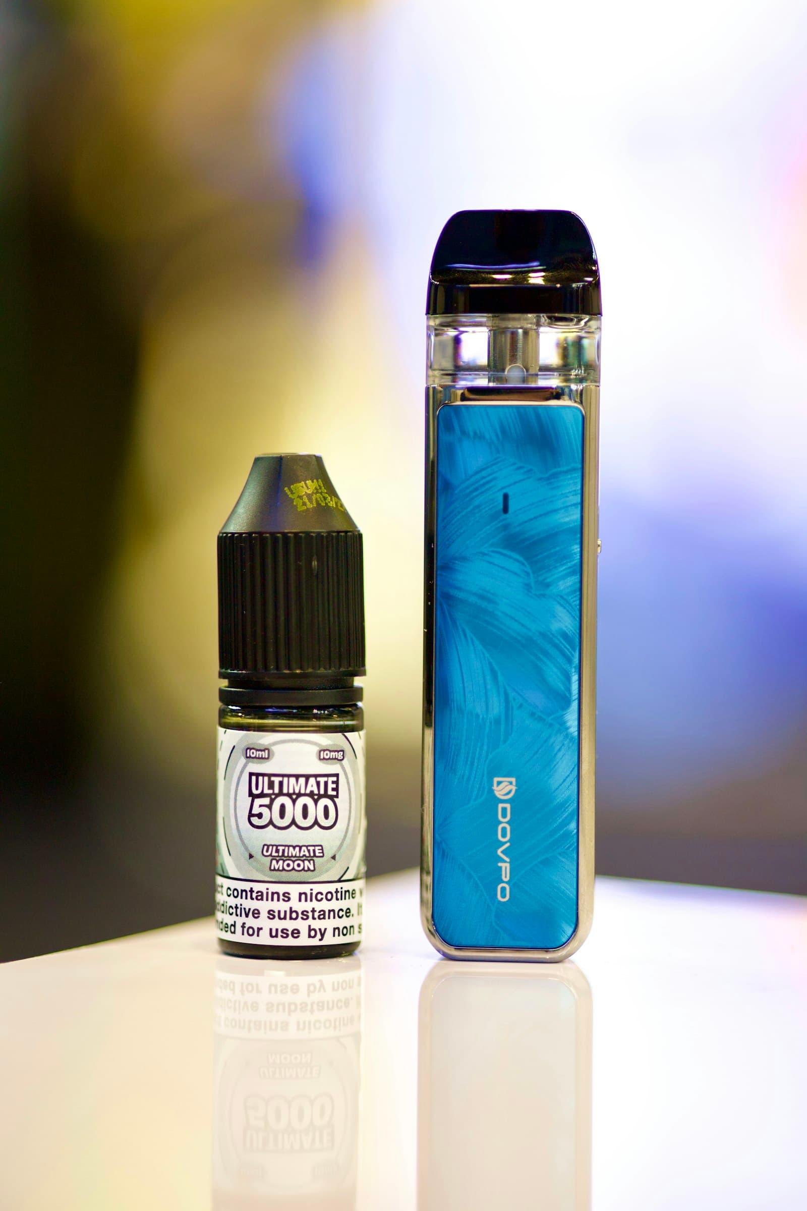 A pod vape kit standing upright next to a bottle of nicotine salt e-liquid