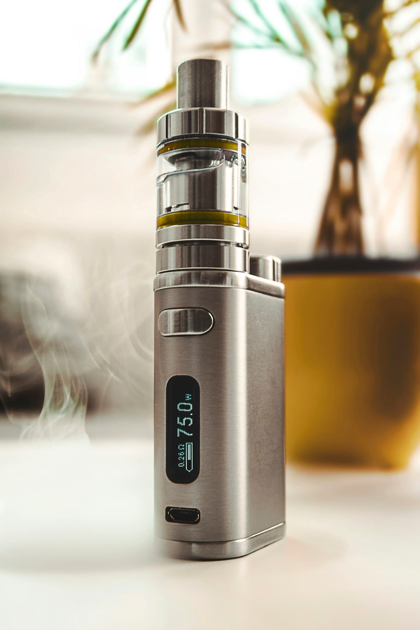 A refillable vape tank with a visible e-liquid fill window sitting on a table