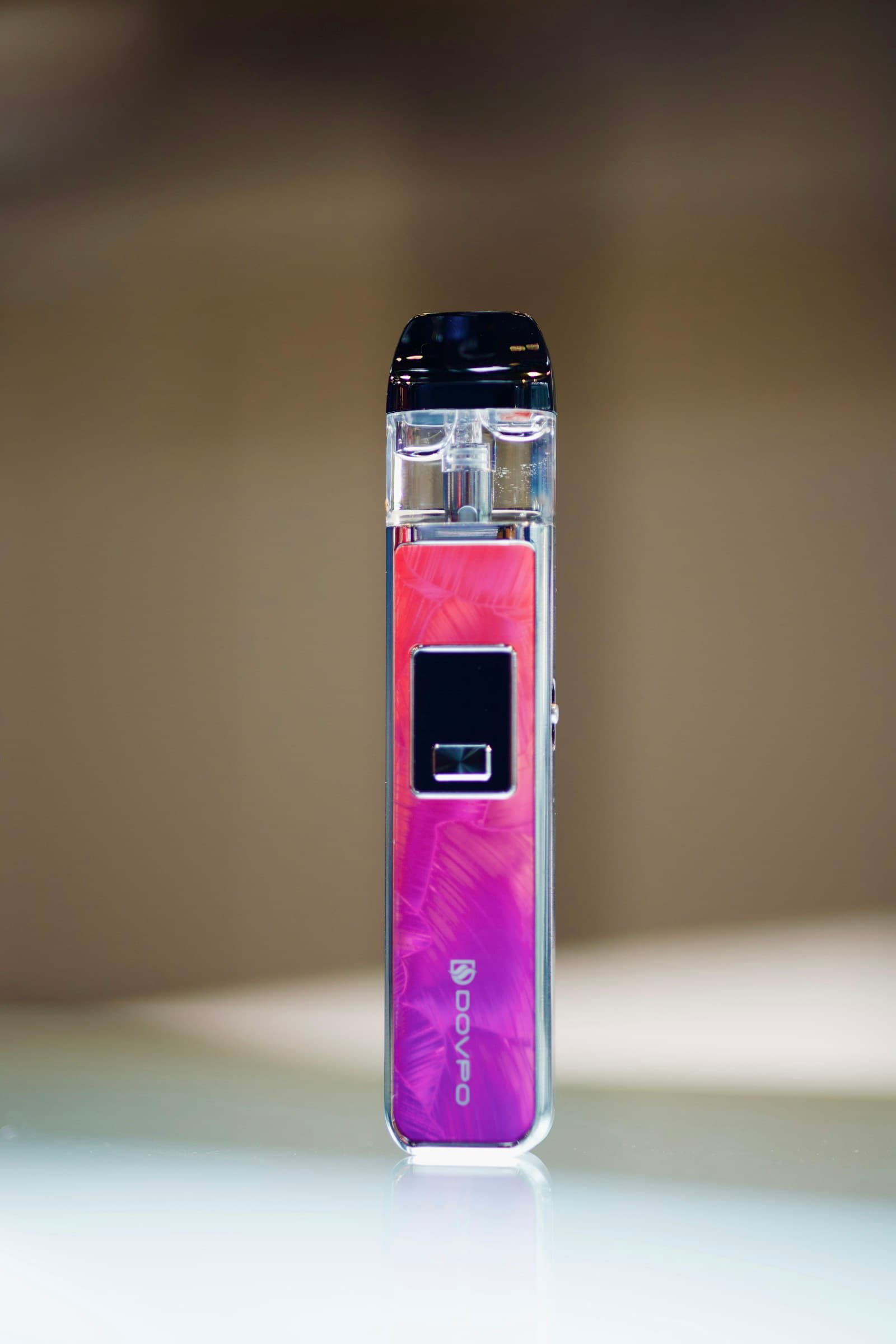 A rechargeable pod vape kit standing upright on a reflective surface